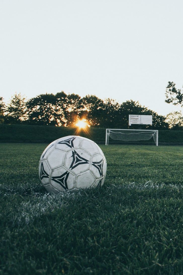 Football on a grass field with a goal in the distance